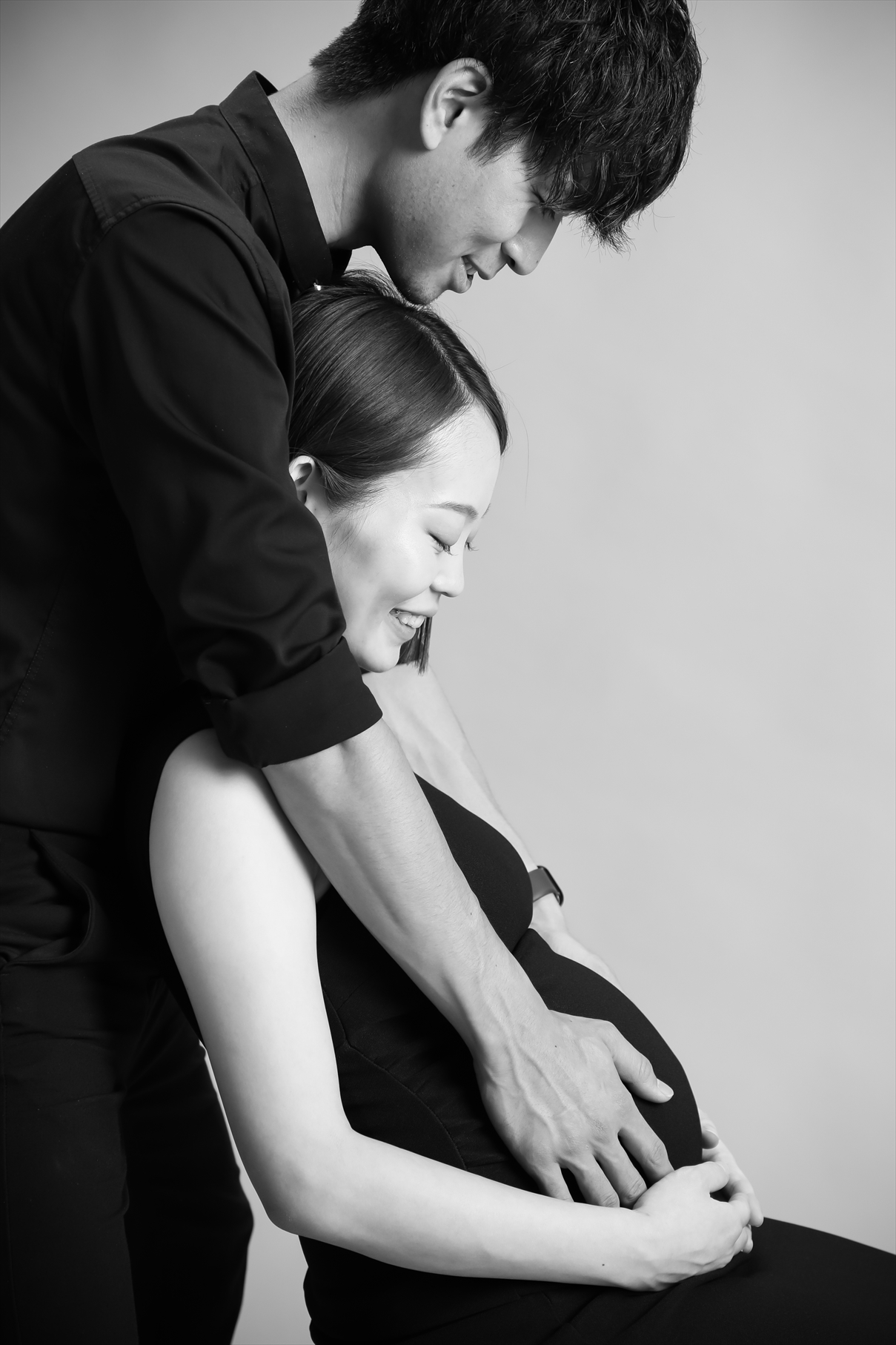 モノクロで撮影したおなかにそっと手を添えるご夫婦の横顔