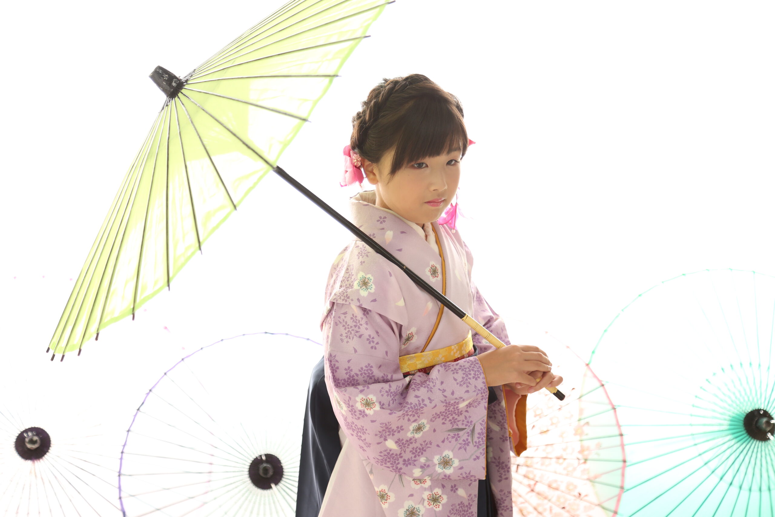 白背景に和傘を広げ薄紫の桜柄の着物と紺袴で佇む女の子