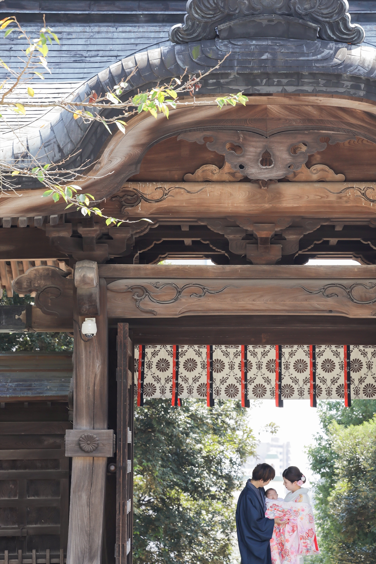 二荒山神社の神門の下で産着の赤ちゃんを抱き寄り添うご夫婦のお宮参り