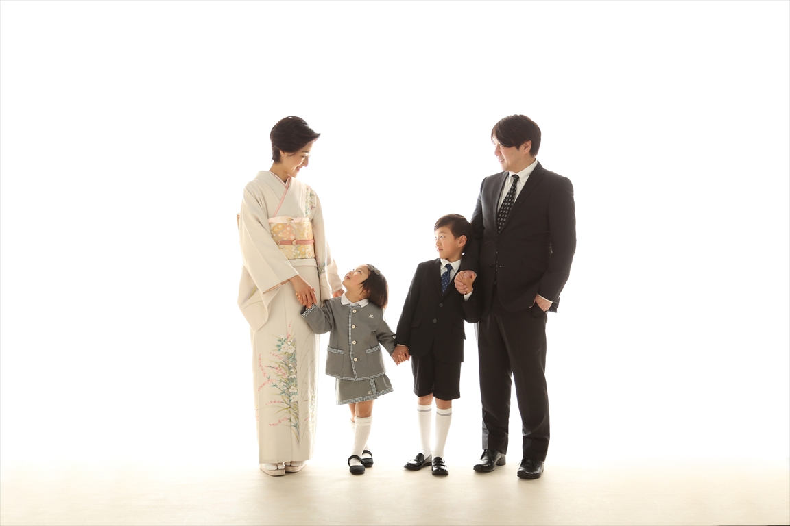 着物のお母様とスーツのお父様が園服の姉弟と手をつなぐご家族4人