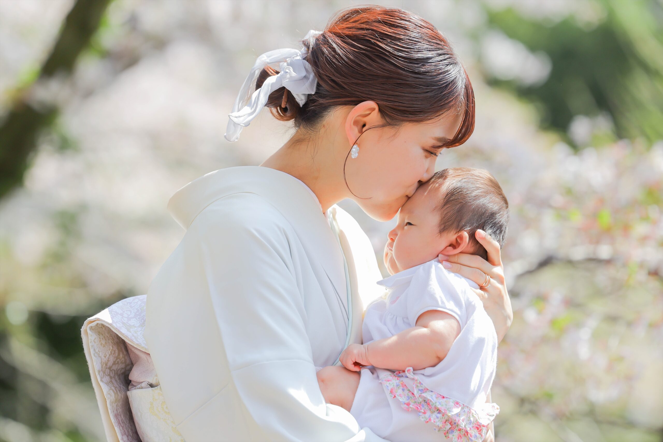 二荒山神社の桜の下で白い着物姿の母が赤ちゃんの額にくちづけるひととき
