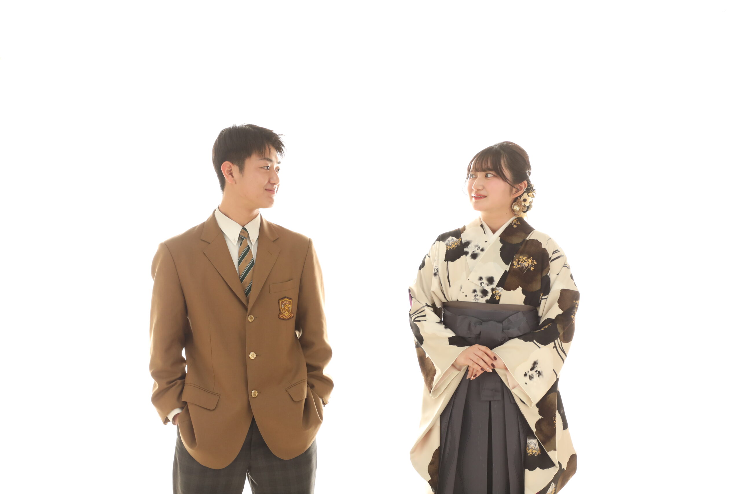 白背景で制服姿の男子と袴姿の女子が顔を見合わせる卒業の記念