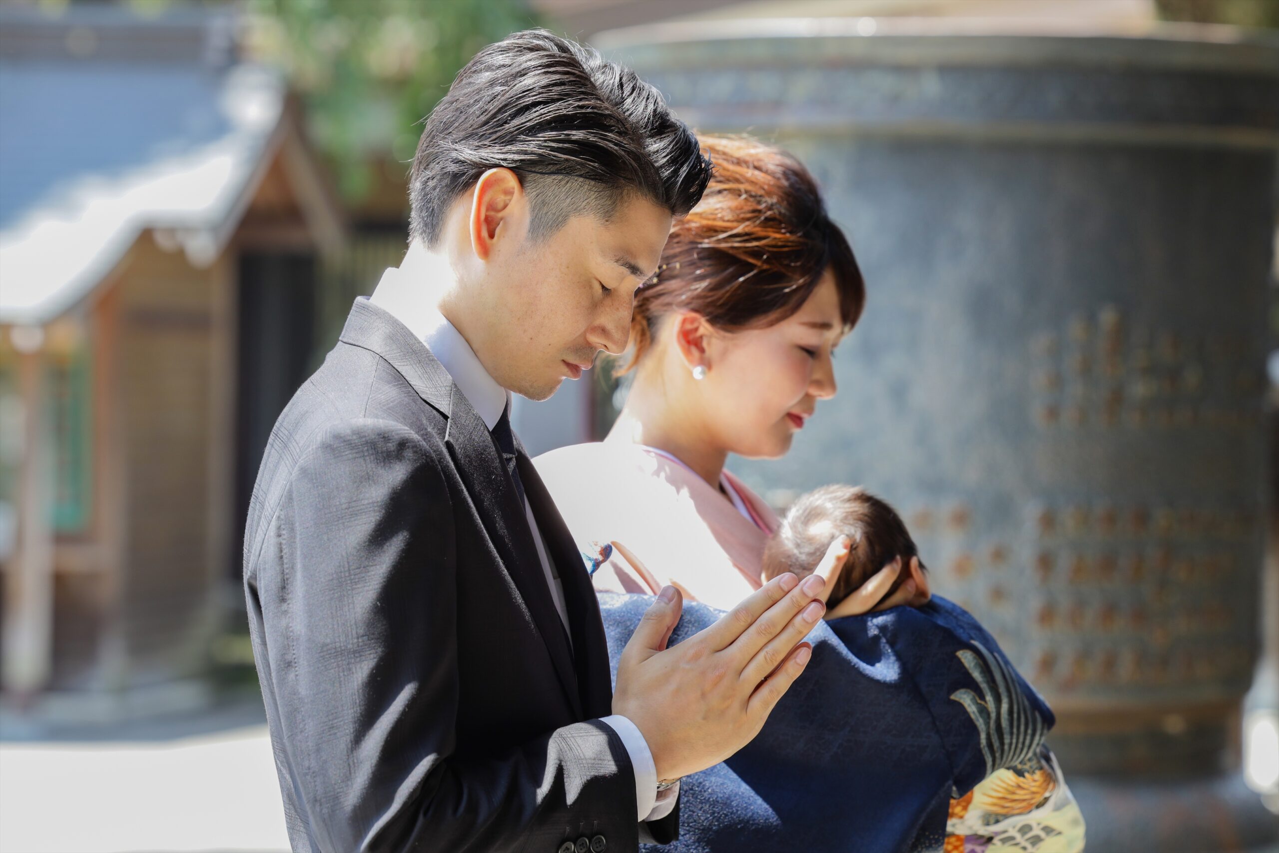 宇都宮二荒山神社の境内で赤ちゃんを抱きしめ目を閉じて祈るご夫婦