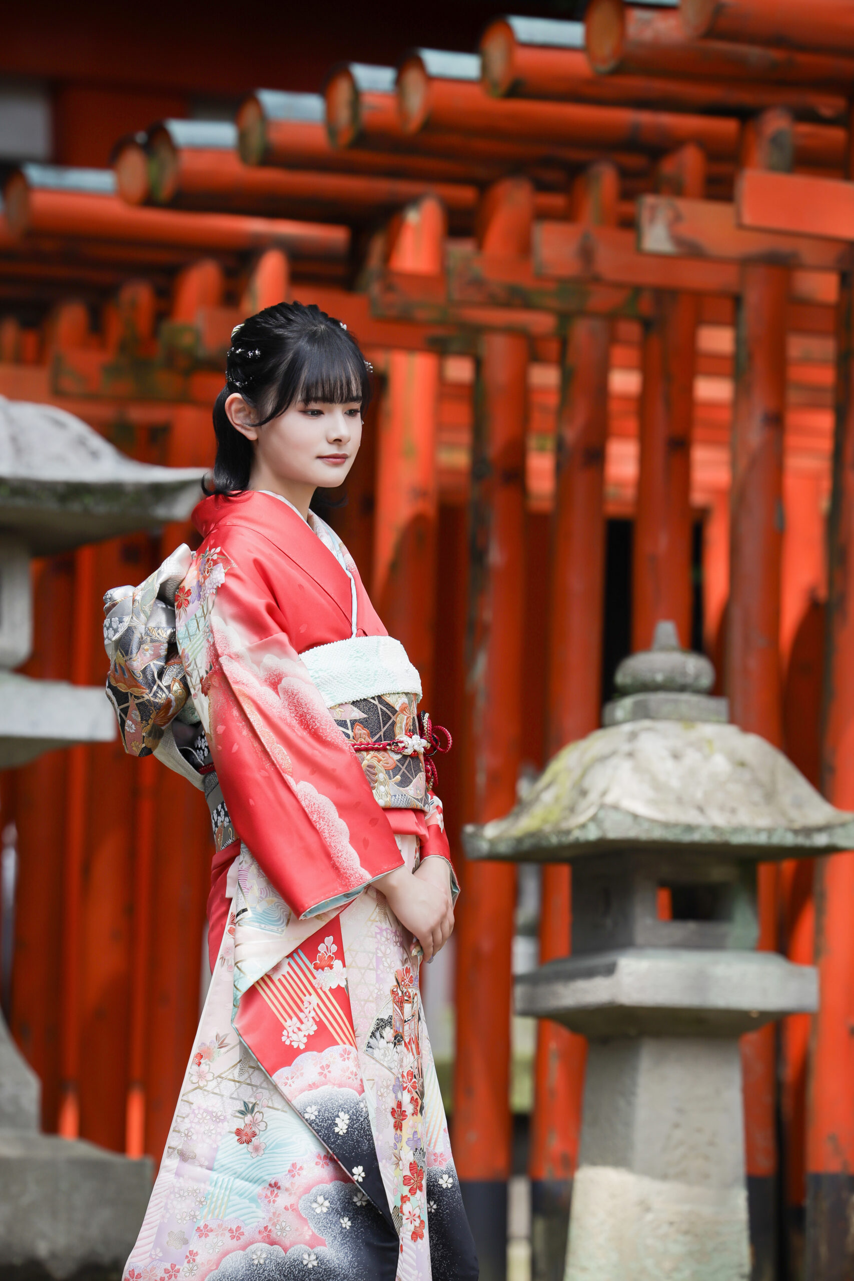 二荒山神社の朱色の鳥居が連なる参道で赤の振袖をまとい佇む新成人