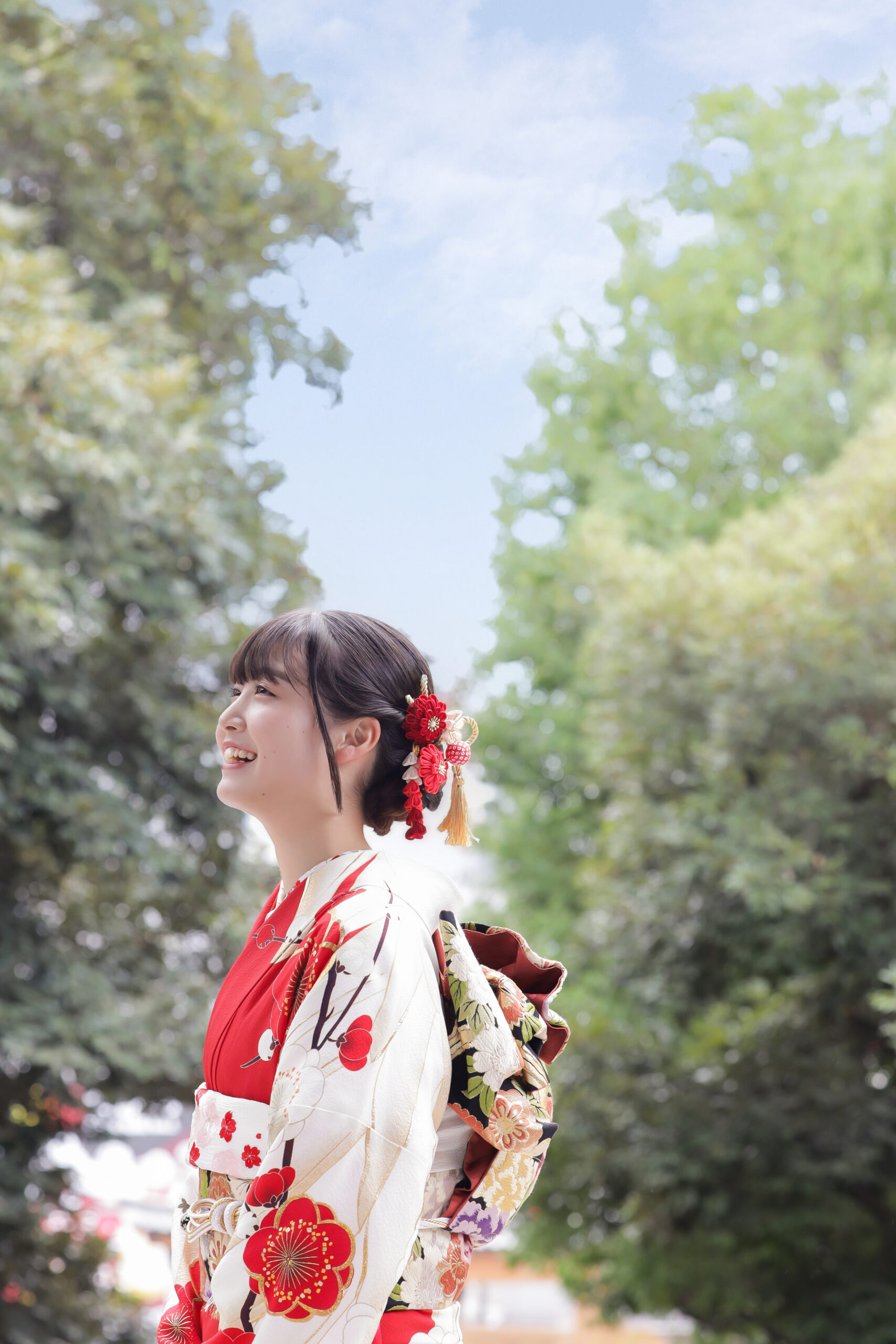 宇都宮二荒山神社の境内で青空を見上げて笑う紅白の梅柄の振袖姿