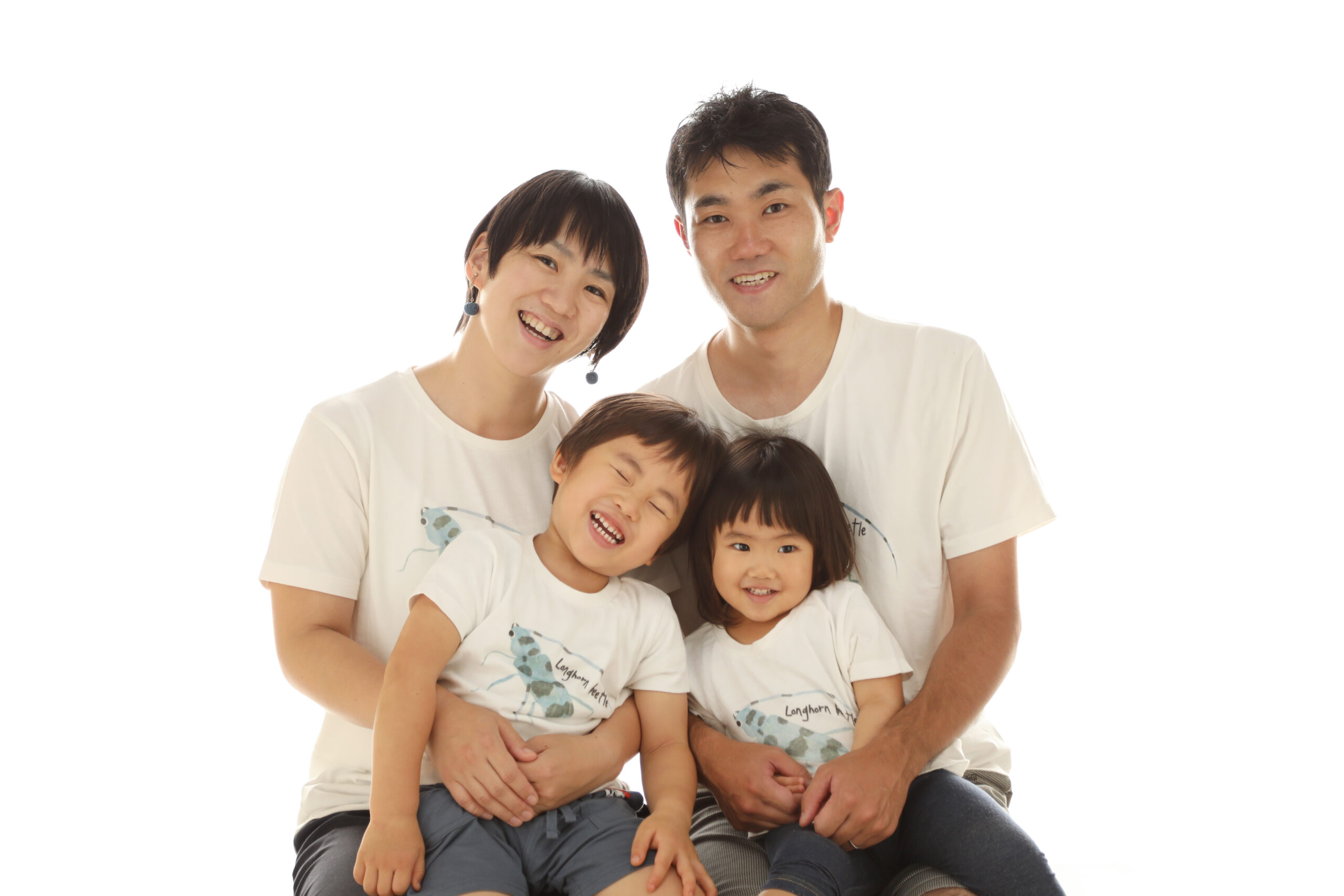 おそろいの白いTシャツで肩を寄せ合って笑うご家族4人