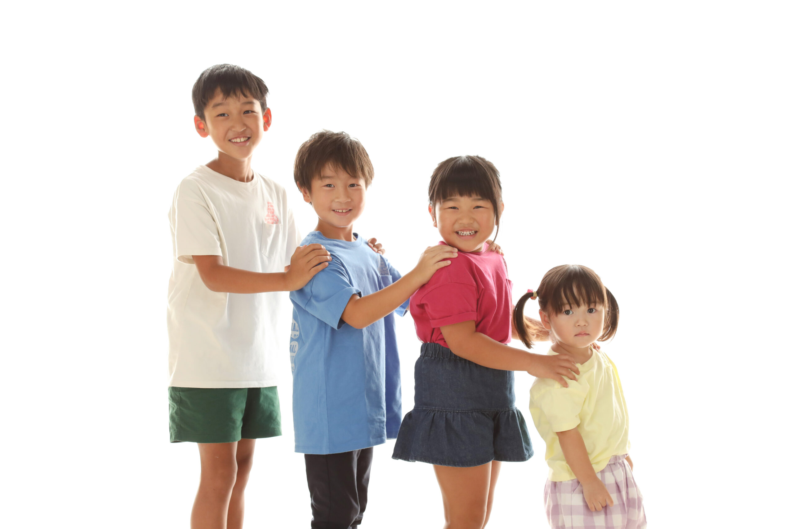 前の子の肩に手をのせて一列に並ぶ4人きょうだいの笑顔