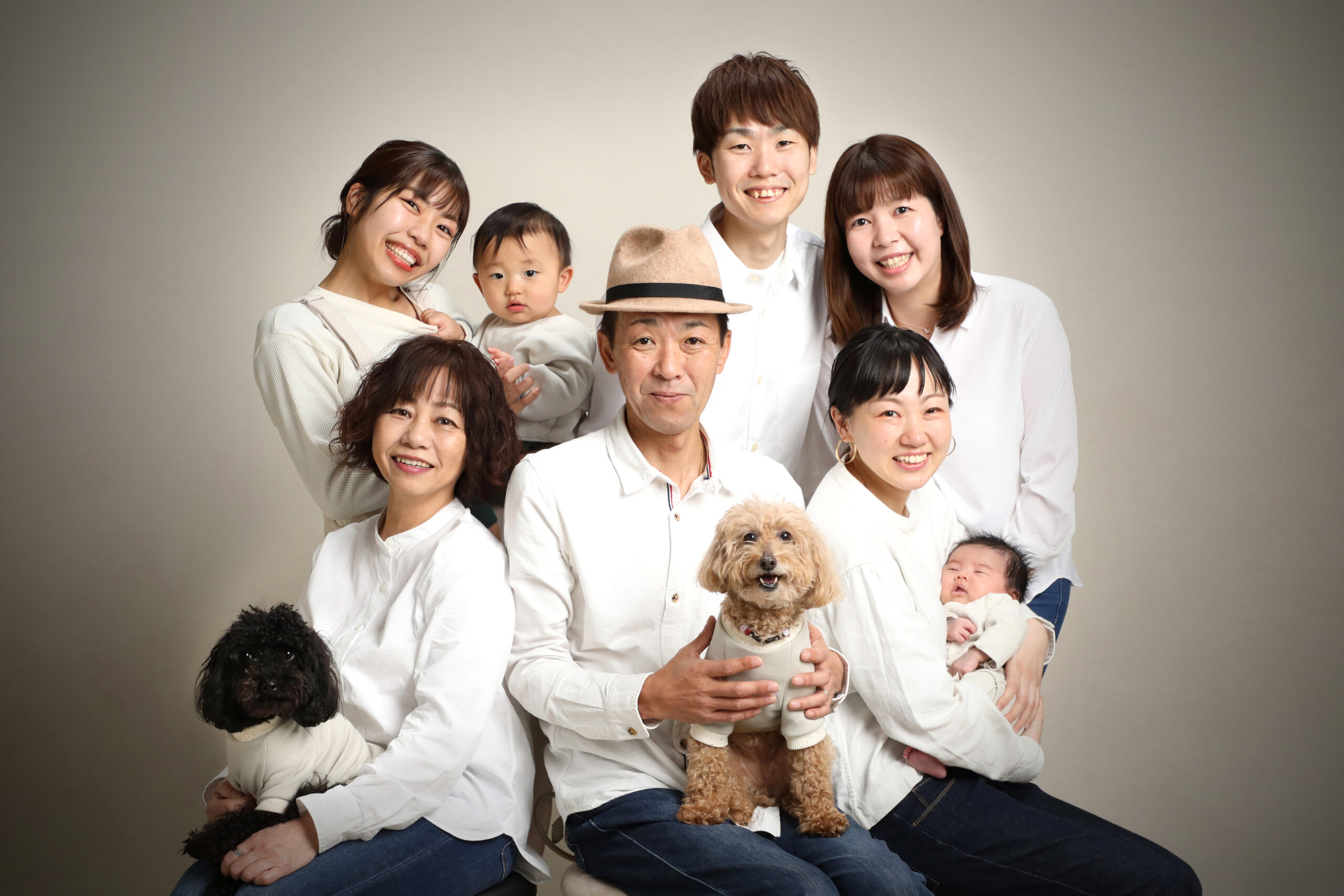 3世代9人と2匹の愛犬が白い装いで集まった大家族の記念撮影