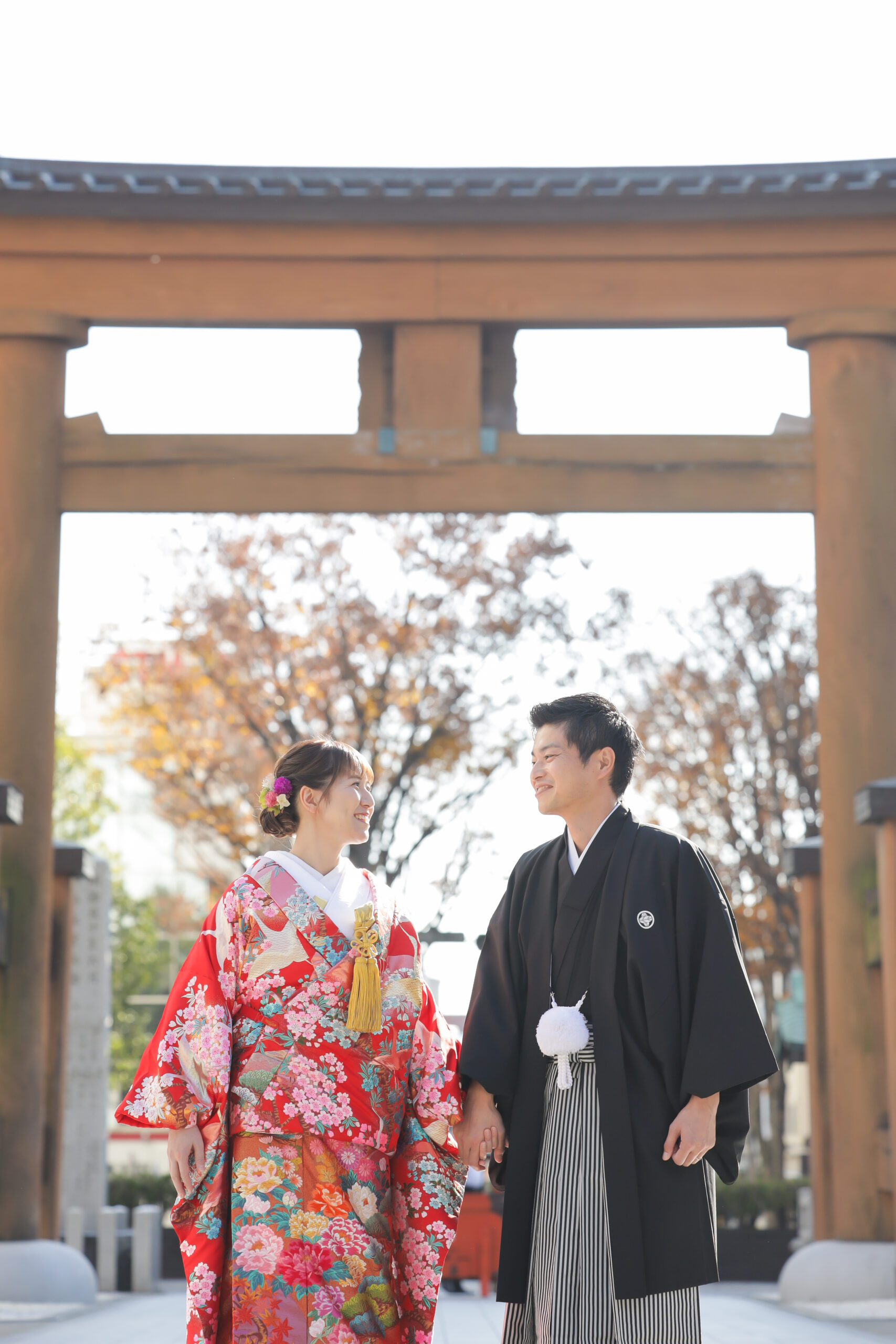 二荒山神社の鳥居をくぐり顔を見合わせて笑う色打掛と紋付袴のお二人